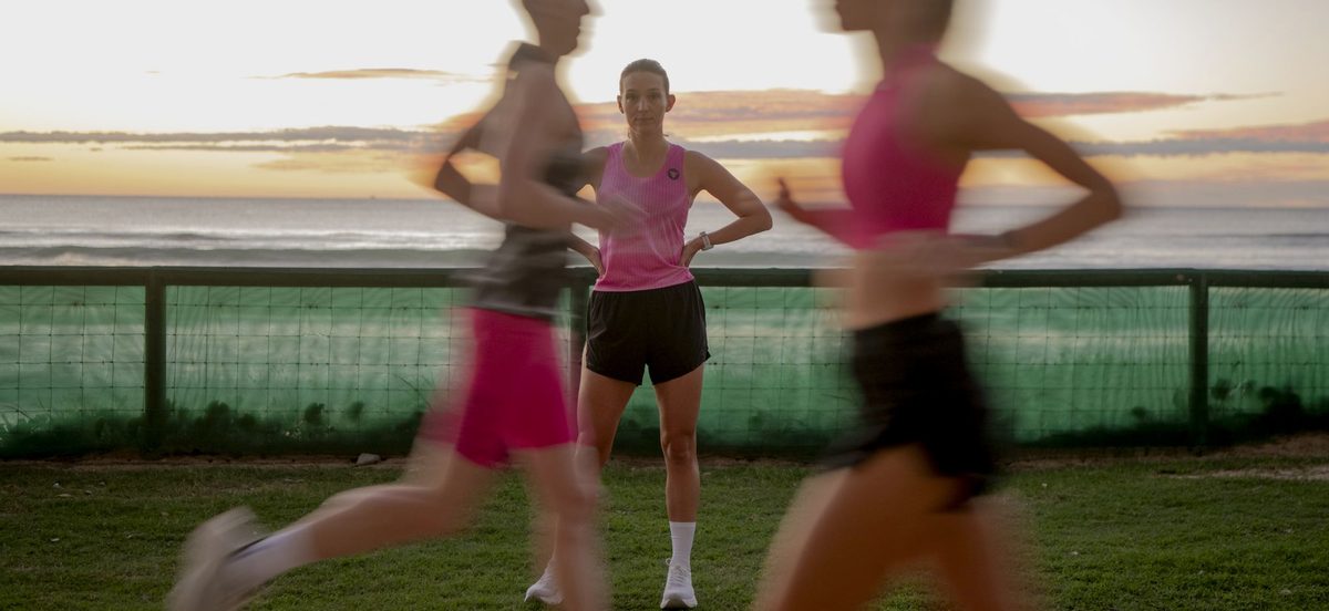 Runner standing on the esplanade as runners pass at sunrise