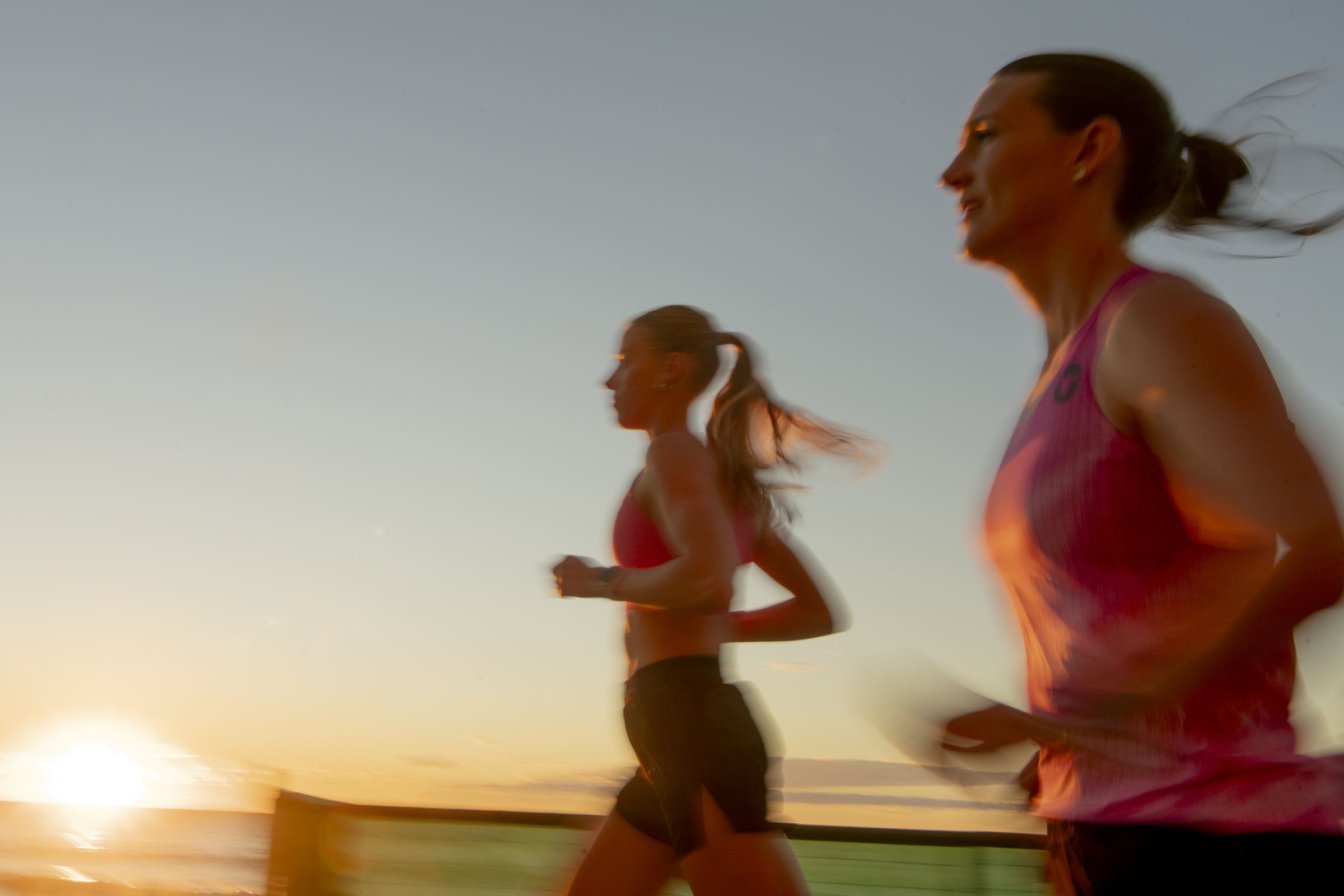 Two runners moving along the Gold Coast esplanade at sunrise